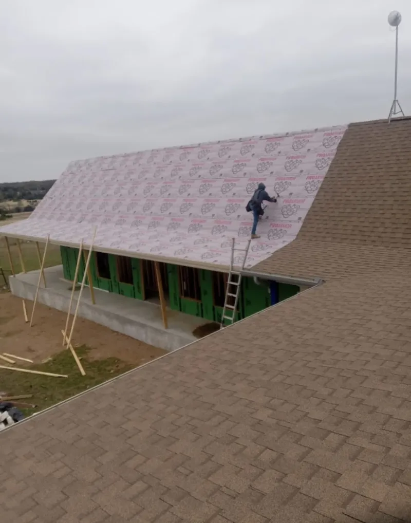 Worker preparing underlayment for a metal roof installation in Commerce